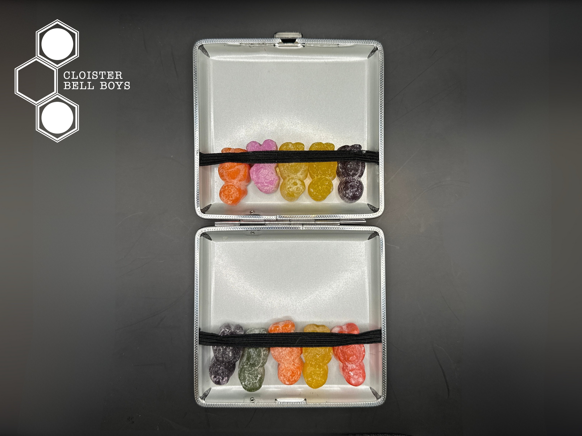 An open cigarette case with resin jelly babies inside on a black background